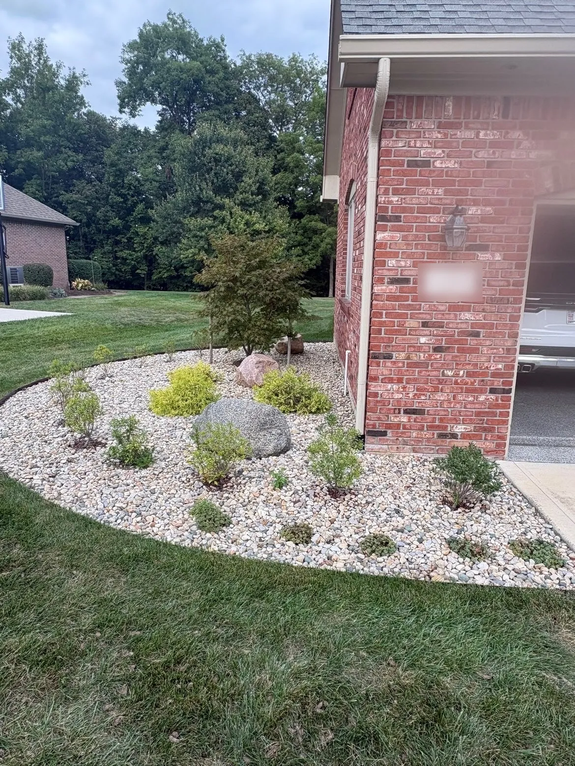 Before: a river-rock bed with boulders and plants along a brick house.
